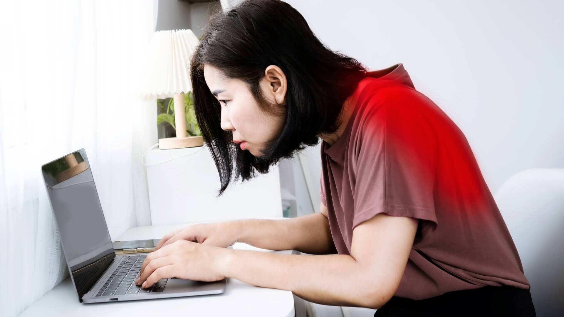 A woman hunches over he laptop