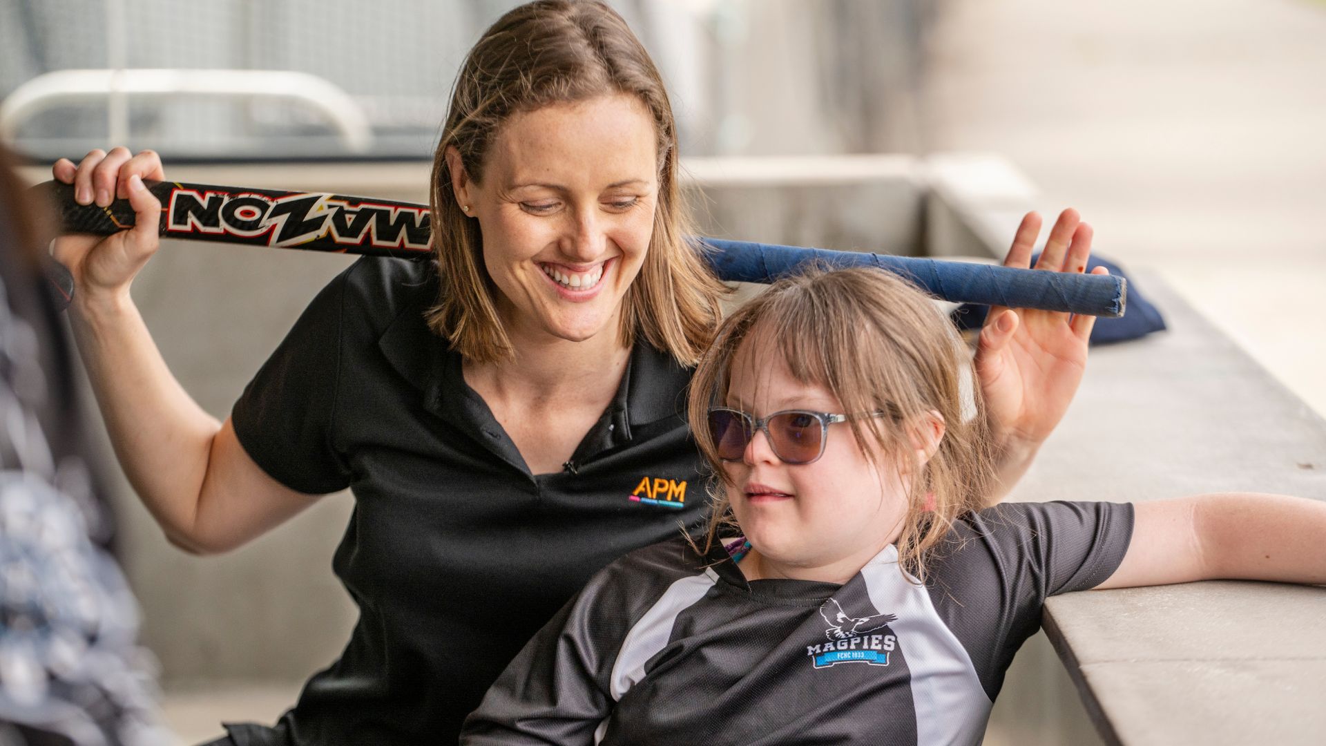 Ellie Cole holding a hockey stick with a young girl