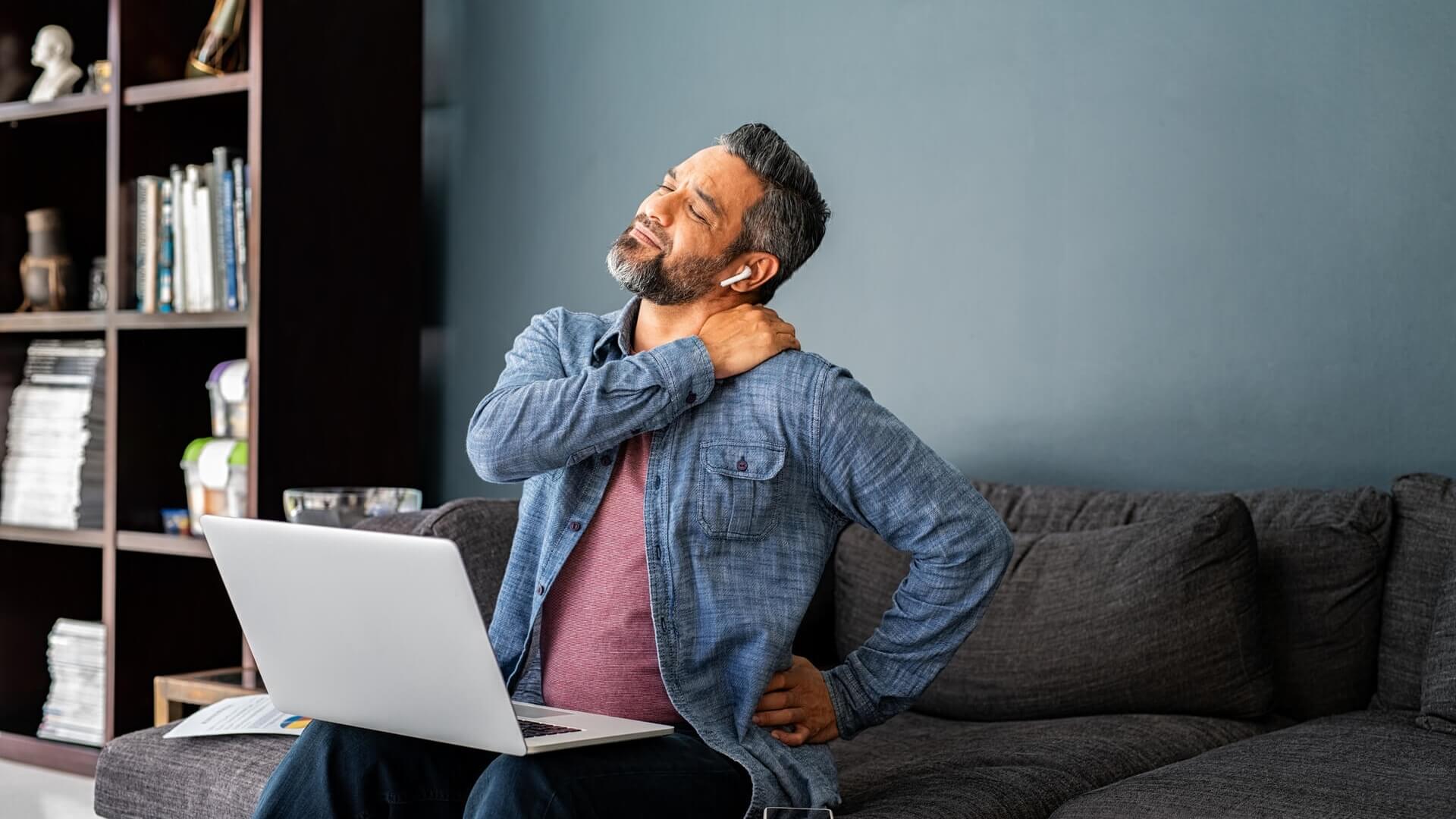 A man sitting on the couch stretches his back and shoulders