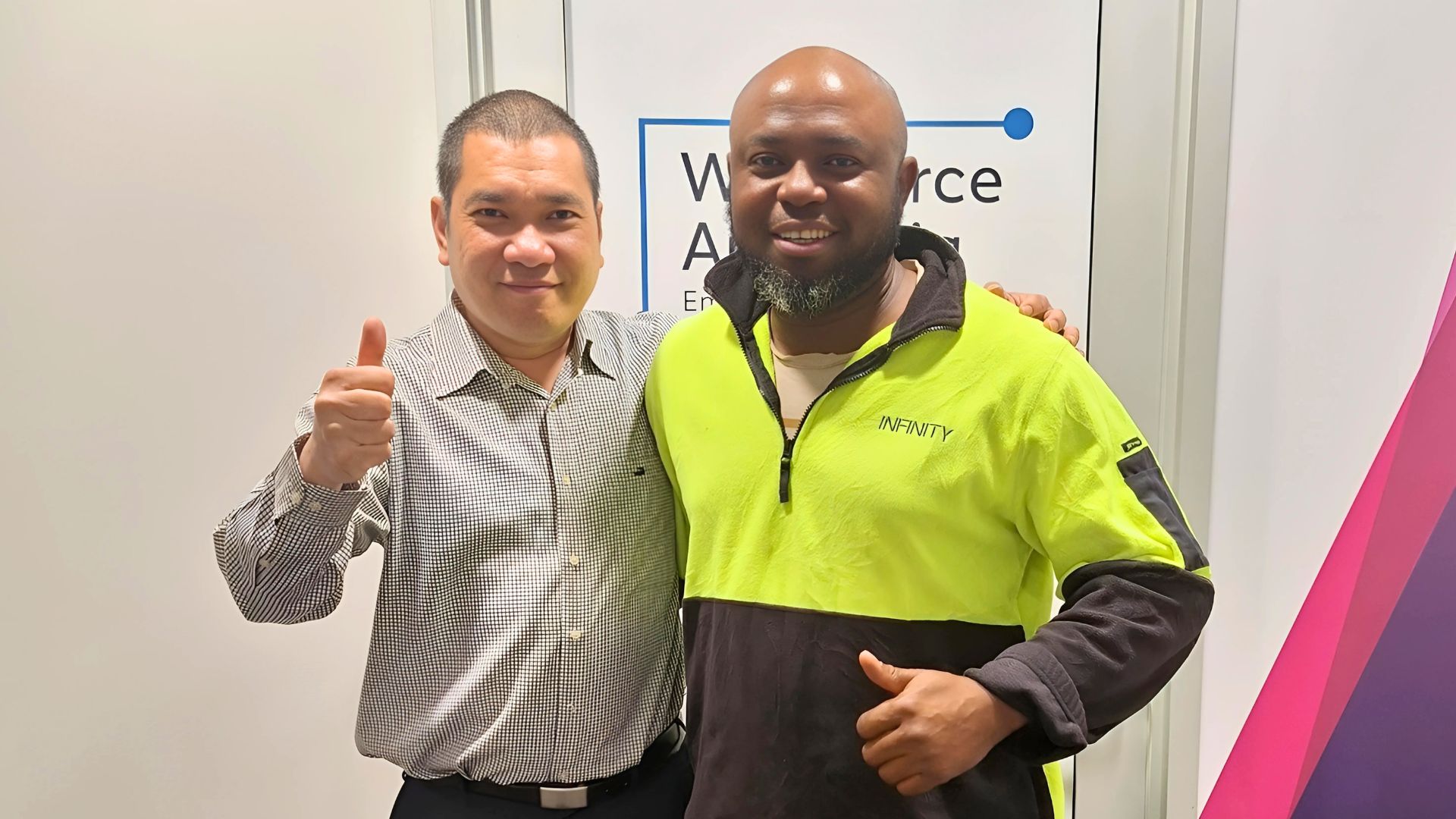 Two men stand together and smile outside an APM Employment Services branch