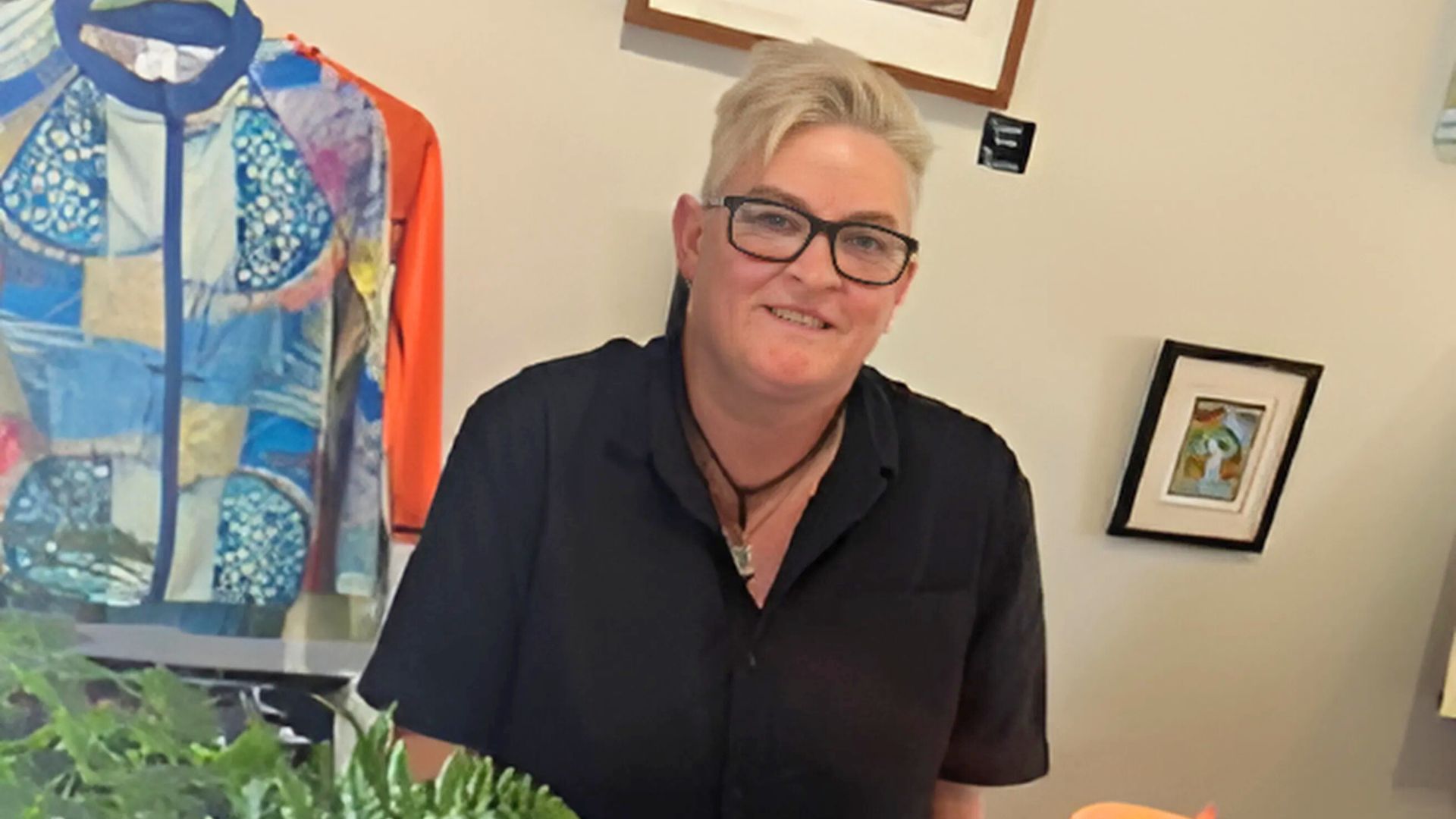 Joanne smiles behind a counter at the art space she set up with support from Self-Employment Assistance