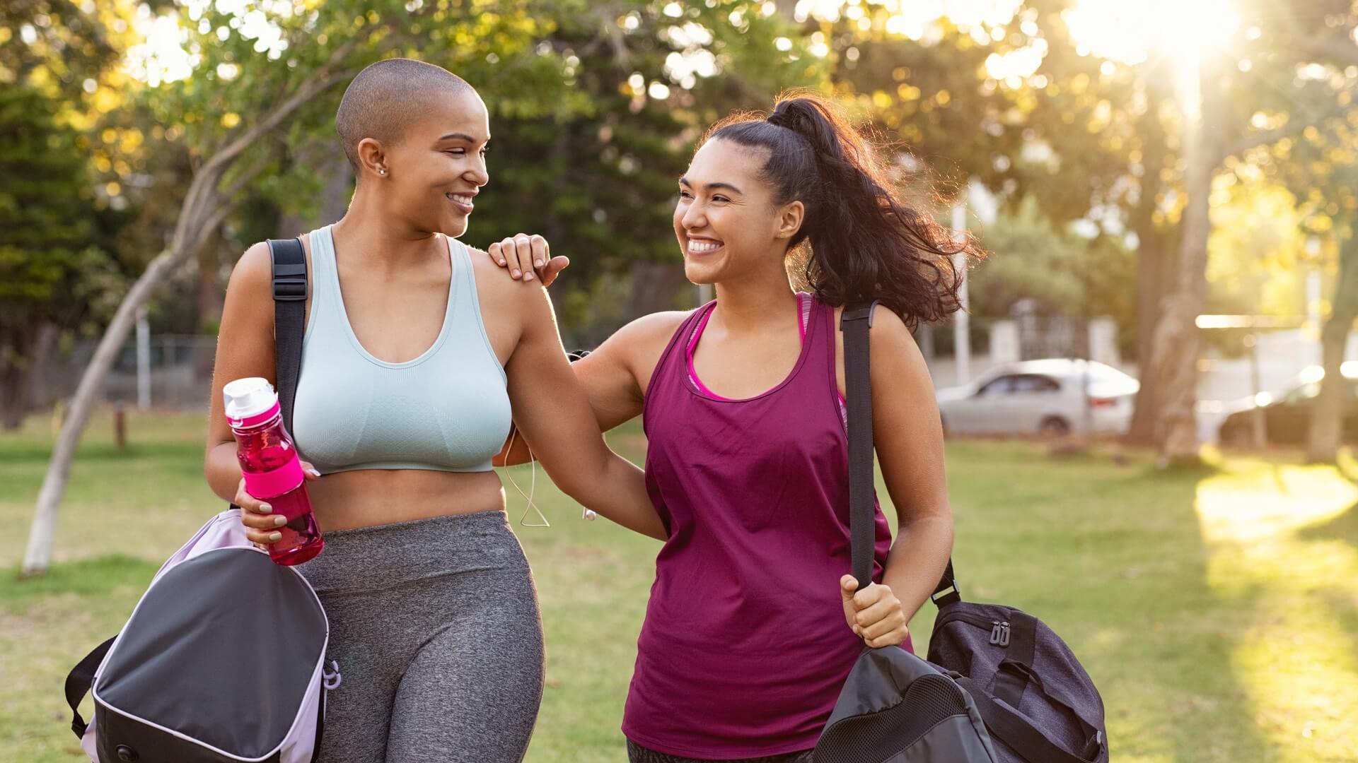 Two women happily walking to an outdoor exercise class